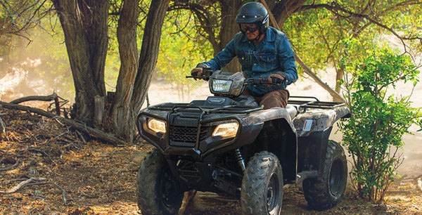 A man in a flannel shirt and helmet riding a 4 wheeler from I 69 Motorsports in Union City, TN